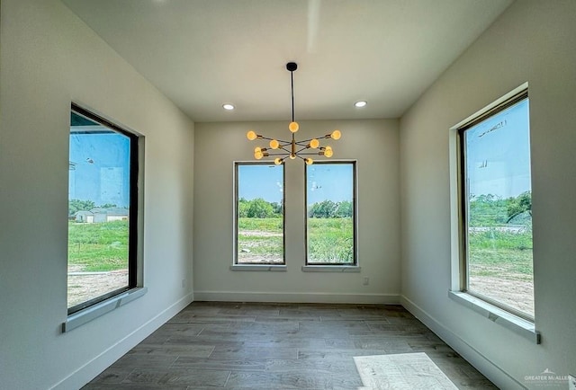 unfurnished dining area featuring hardwood / wood-style flooring and a notable chandelier