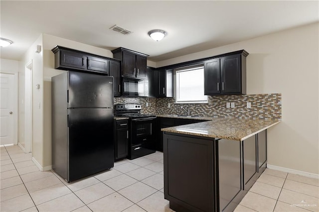 kitchen featuring tasteful backsplash, light stone counters, light tile patterned floors, and black appliances