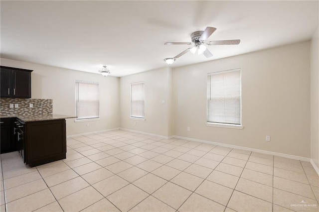 interior space featuring ceiling fan, light stone counters, light tile patterned floors, and backsplash