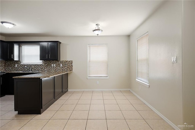 kitchen with light tile patterned flooring, dark stone countertops, and tasteful backsplash