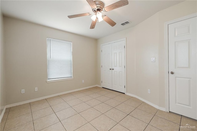 unfurnished bedroom with light tile patterned floors, a closet, and ceiling fan