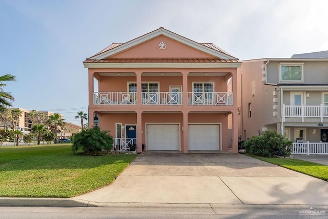 131 E Hibiscus St, South Padre Island, TX 78597 - view of front of house featuring a balcony, driveway, stucco siding, a front lawn, and a garage