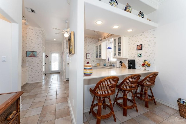 131 E Hibiscus St, South Padre Island, TX 78597 - kitchen with wallpapered walls, glass insert cabinets, visible vents, and ornamental molding