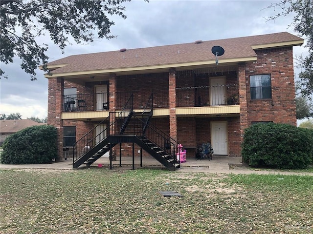 back of house featuring a lawn and a balcony