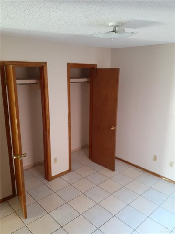 unfurnished bedroom with light tile patterned floors, a textured ceiling, and ceiling fan