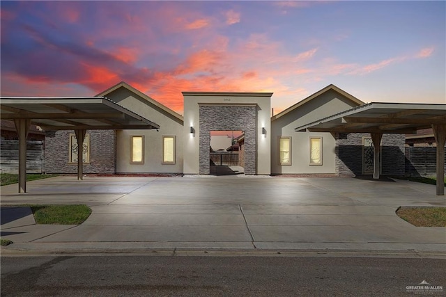 modern home with stone siding, concrete driveway, and stucco siding