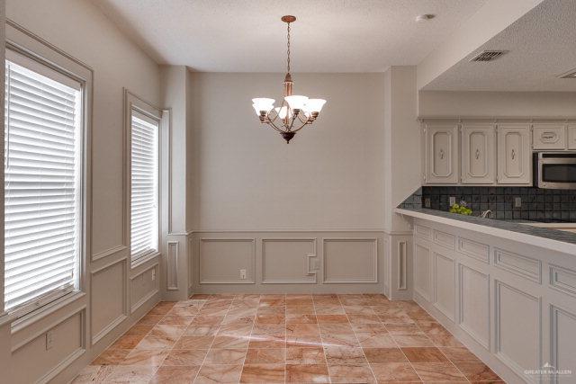 2114 Colorado St, Mission, TX 78572 - unfurnished dining area with plenty of natural light, a decorative wall, a chandelier, and wainscoting