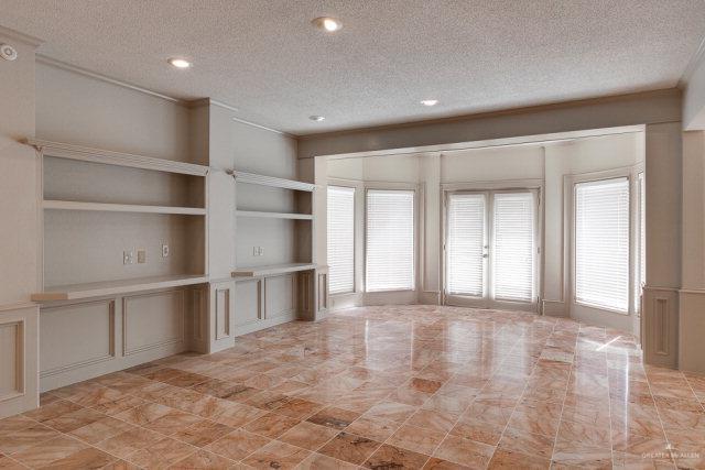 2114 Colorado St, Mission, TX 78572 - unfurnished living room featuring a textured ceiling, a decorative wall, built in shelves, and recessed lighting