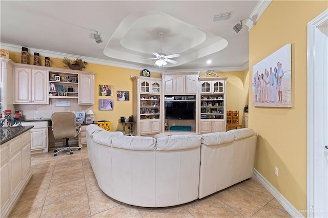 tiled living room with ceiling fan, a raised ceiling, and ornamental molding