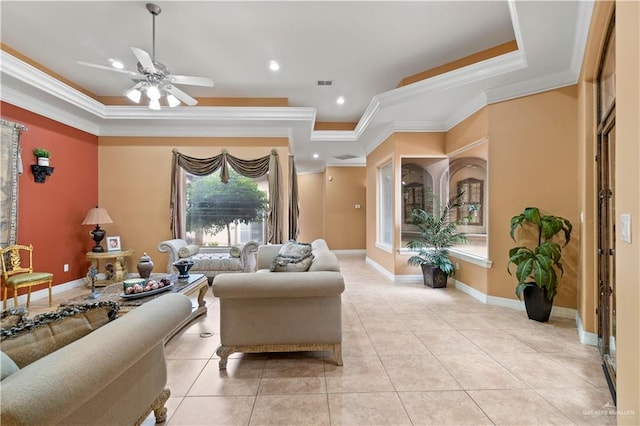 living room featuring a tray ceiling, crown molding, light tile patterned flooring, and ceiling fan