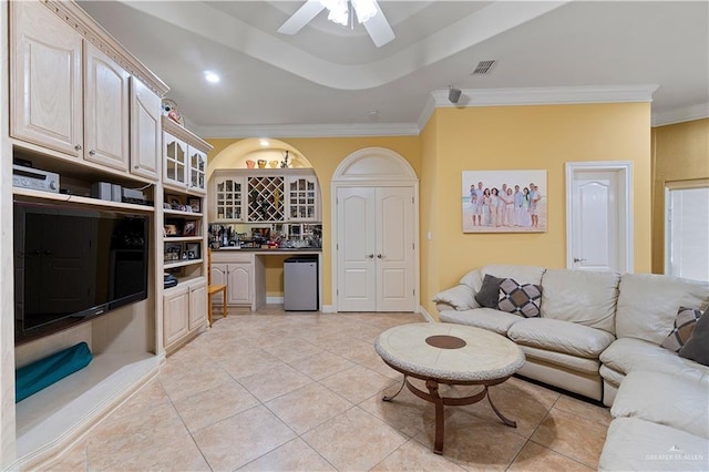 living room with bar area, ceiling fan, light tile patterned floors, and ornamental molding