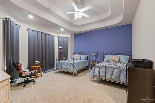 carpeted bedroom with a tray ceiling and ceiling fan