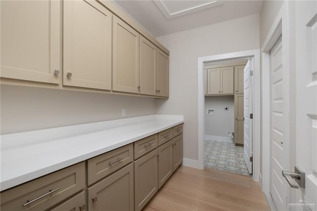 laundry area featuring cabinet space, electric dryer hookup, light wood-style floors, and baseboards