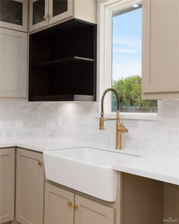 kitchen view of a sink, backsplash, and light countertops