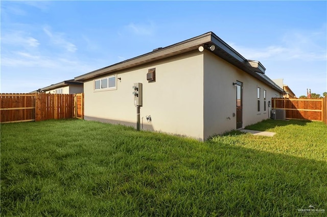 view of property exterior with a lawn and central AC