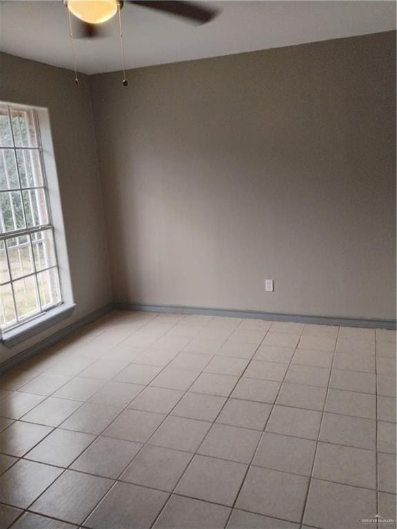 empty room with ceiling fan and light tile patterned flooring