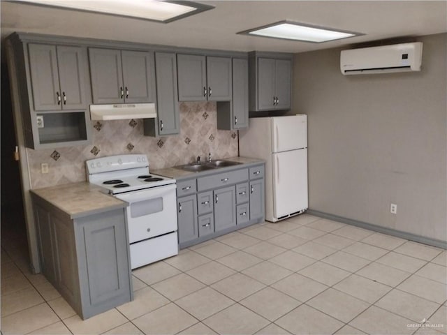 kitchen featuring gray cabinetry, white appliances, an AC wall unit, sink, and light tile patterned floors