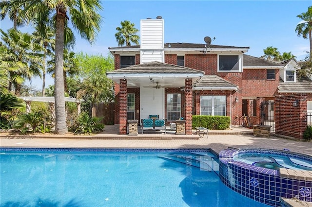 back of house with ceiling fan, a swimming pool with hot tub, and a patio