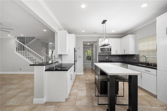 kitchen with pendant lighting, white cabinetry, sink, and a breakfast bar area