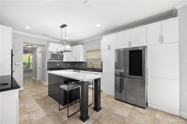 kitchen featuring sink, hanging light fixtures, crown molding, decorative backsplash, and appliances with stainless steel finishes