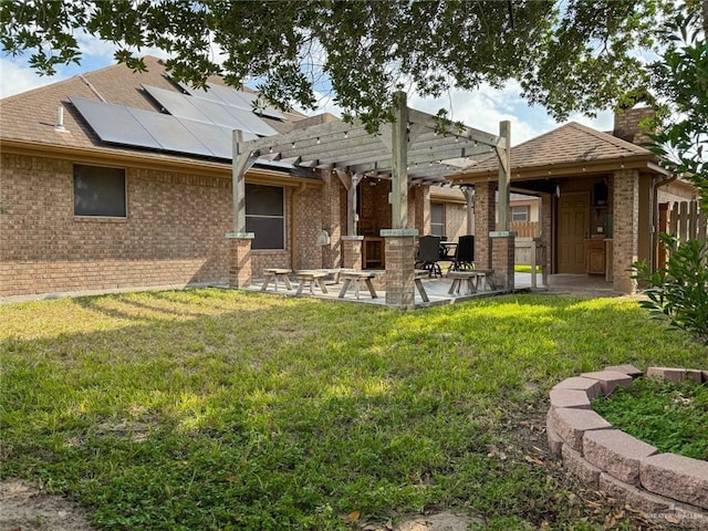 back of property with solar panels, a patio, a pergola, and a lawn