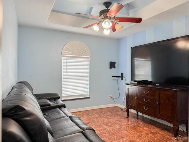 living room with ceiling fan, dark tile patterned floors, and a tray ceiling