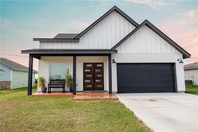 modern farmhouse featuring central air condition unit, a yard, covered porch, and a garage