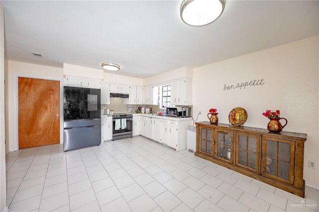 kitchen with white cabinets, light tile patterned floors, and appliances with stainless steel finishes