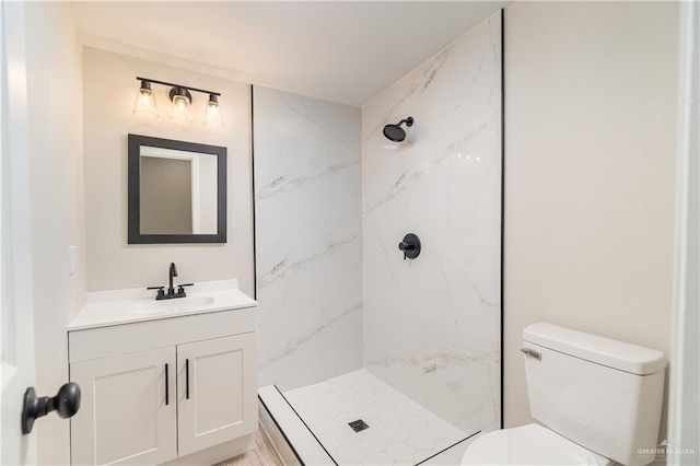 bathroom featuring toilet, vanity, and a tile shower