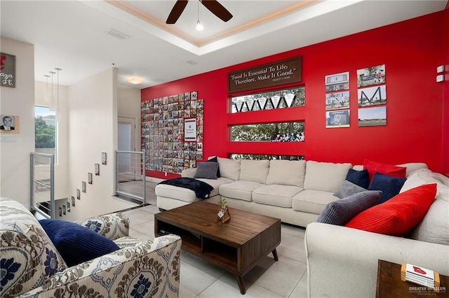 tiled living room featuring ceiling fan and a tray ceiling