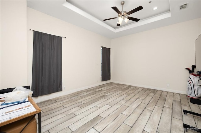 interior space with ceiling fan, light wood-type flooring, and a tray ceiling