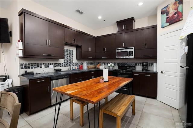 kitchen with light tile patterned floors, black appliances, decorative backsplash, dark brown cabinets, and sink