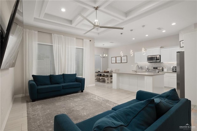 tiled living room with beam ceiling, sink, ceiling fan with notable chandelier, and coffered ceiling