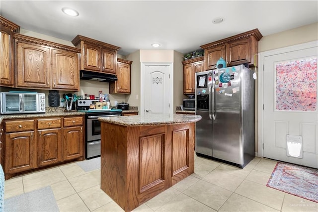 512 S Mina De Oro St, Mission, TX 78572 - kitchen with appliances with stainless steel finishes, under cabinet range hood, a kitchen island, light stone countertops, and light tile patterned floors