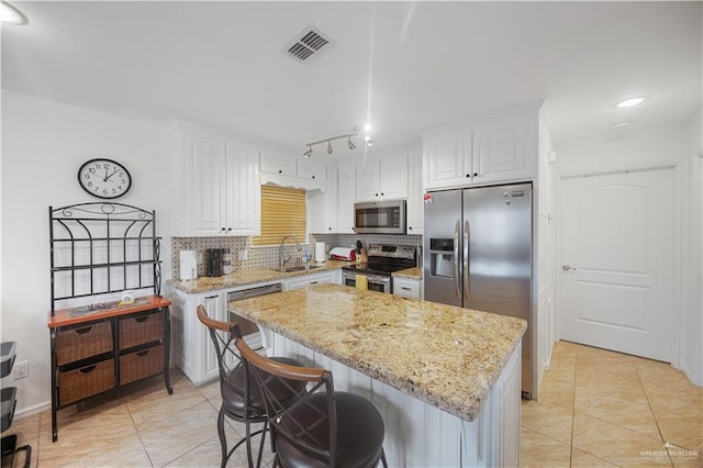 kitchen with visible vents, appliances with stainless steel finishes, a center island, tasteful backsplash, and white cabinets