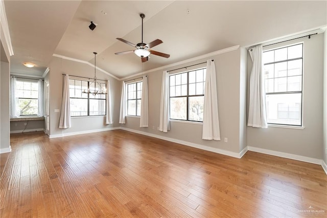 empty room with vaulted ceiling, ornamental molding, ceiling fan with notable chandelier, and hardwood / wood-style floors