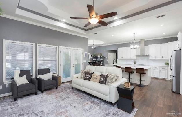 living room featuring a tray ceiling, ornamental molding, and light hardwood / wood-style floors