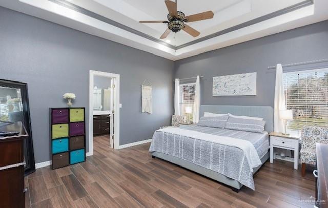 bedroom featuring ceiling fan, connected bathroom, dark hardwood / wood-style floors, and a tray ceiling