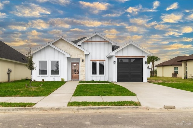 modern farmhouse with an attached garage, a lawn, board and batten siding, and driveway