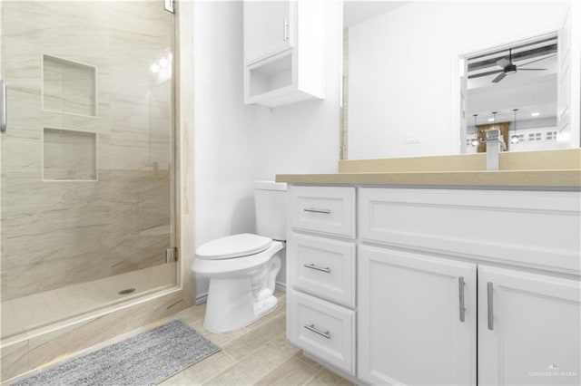 full bathroom with vanity, toilet, a marble finish shower, and ceiling fan