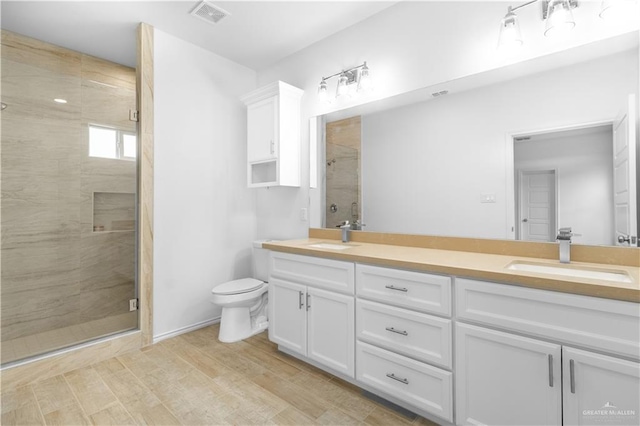 bathroom featuring visible vents, double vanity, a sink, a shower stall, and toilet