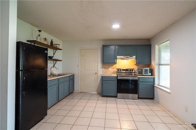 1306 Denver St, Edinburg, TX 78541 - kitchen with freestanding refrigerator, stainless steel electric range, under cabinet range hood, open shelves, and blue cabinets