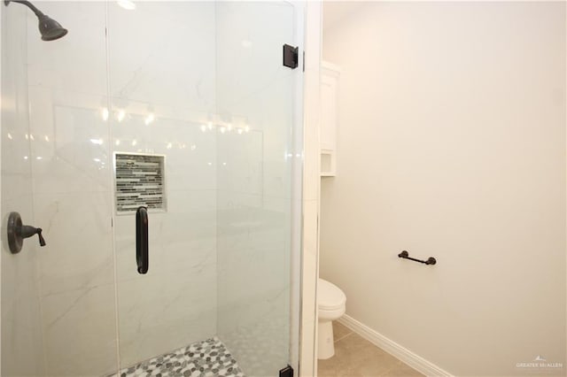 bathroom with tile patterned flooring, toilet, and a shower with shower door