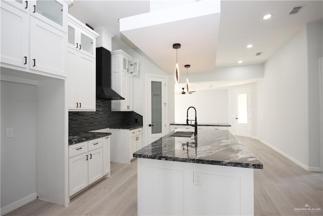 kitchen featuring a center island with sink, decorative light fixtures, and white cabinetry