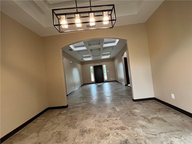 empty room with arched walkways, baseboards, and coffered ceiling