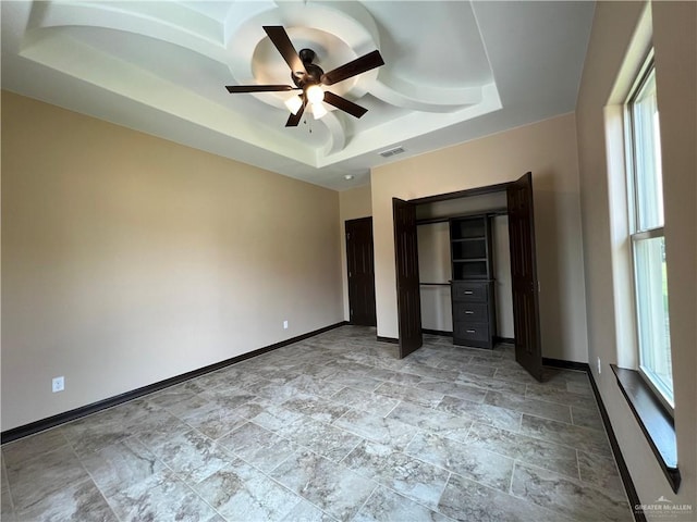 unfurnished bedroom with baseboards, a raised ceiling, visible vents, and stone finish floor
