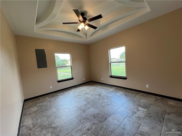 unfurnished room featuring baseboards, ceiling fan, a raised ceiling, and electric panel