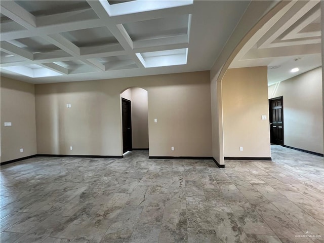 empty room with arched walkways, baseboards, and beam ceiling