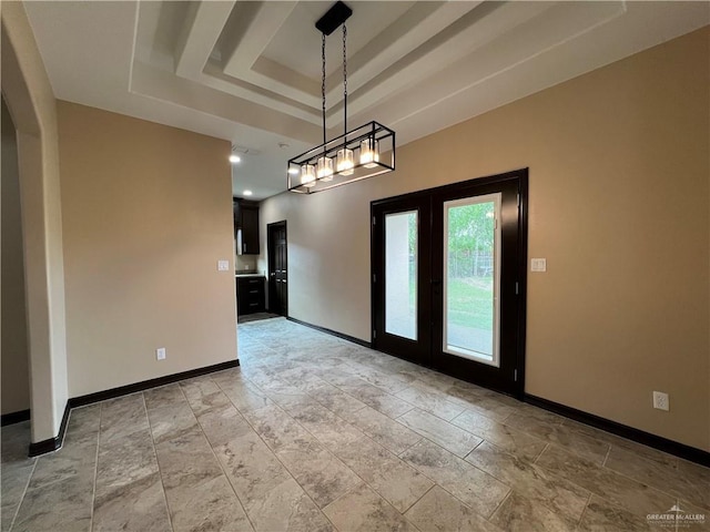 empty room featuring baseboards, stone finish floor, and a tray ceiling
