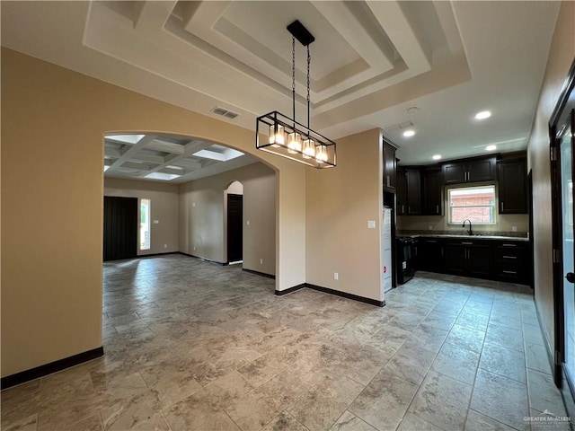 unfurnished dining area with arched walkways, a tray ceiling, baseboards, and coffered ceiling